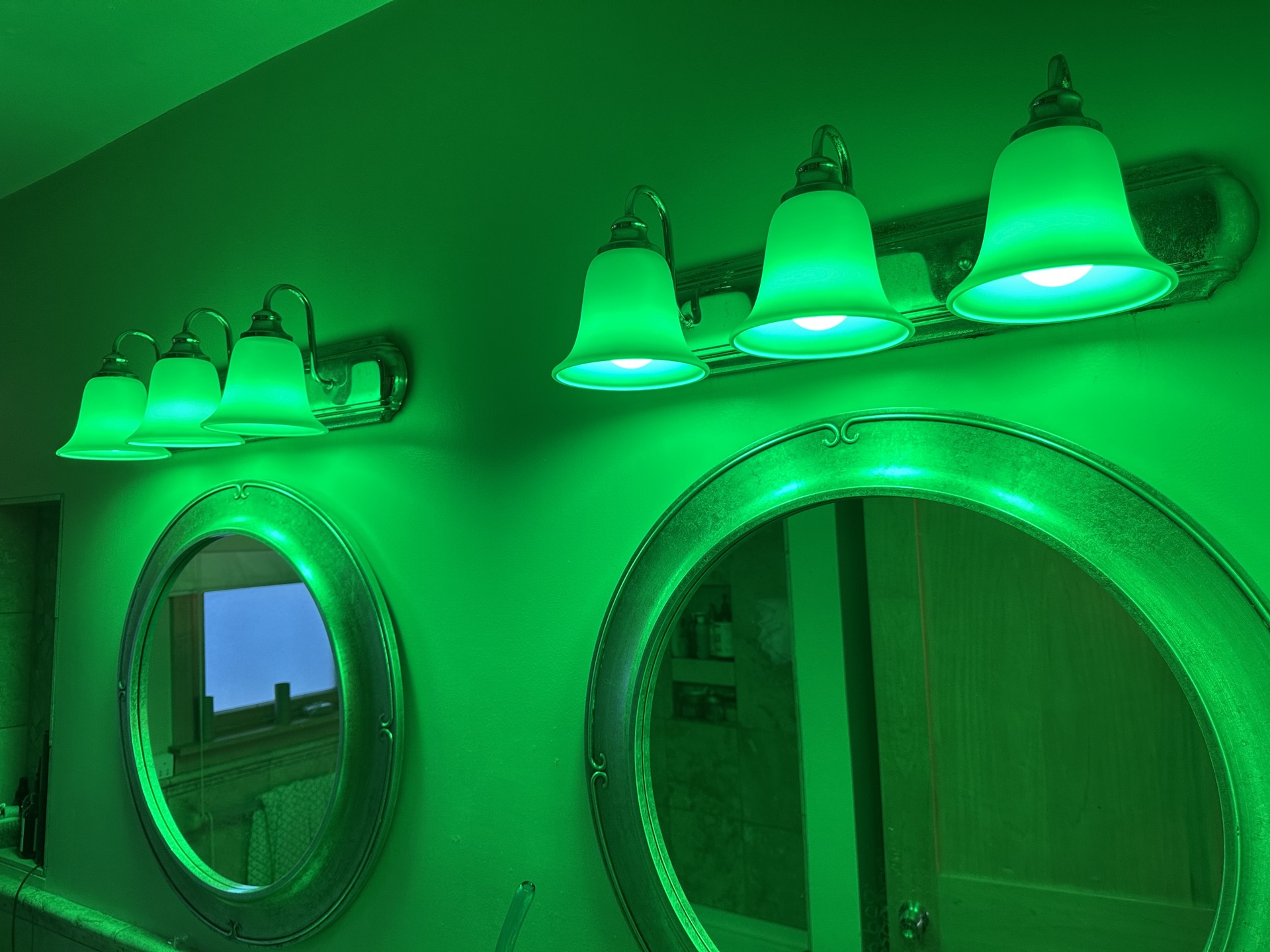 Six bathroom vanity bulbs glowing green, caught mid 'disco' startup after losing their pairing.